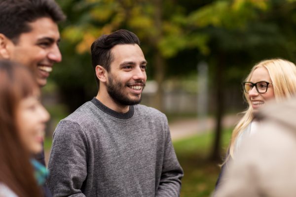 people, friendship, communication and international concept - group of happy friends walking along autumn park